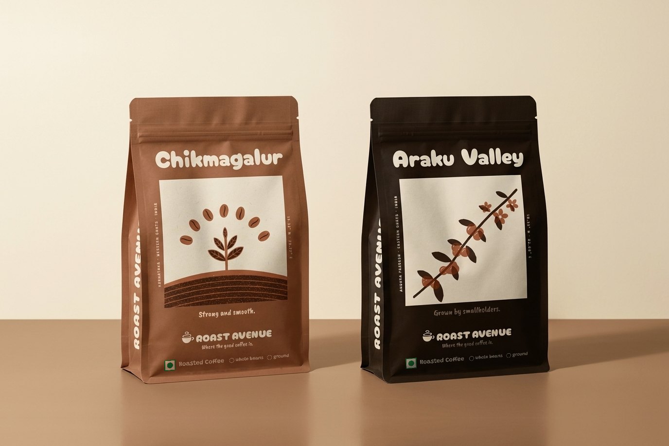 Two pouches of Roast Avenue coffee standing side by side on a tan table against a cream wall: Chikmagalur in terracotta, Araku Valley in dark brown.